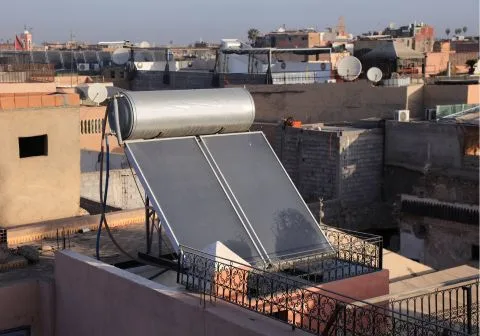 Teknisi pasang solar water heater unit baru di atap rumah